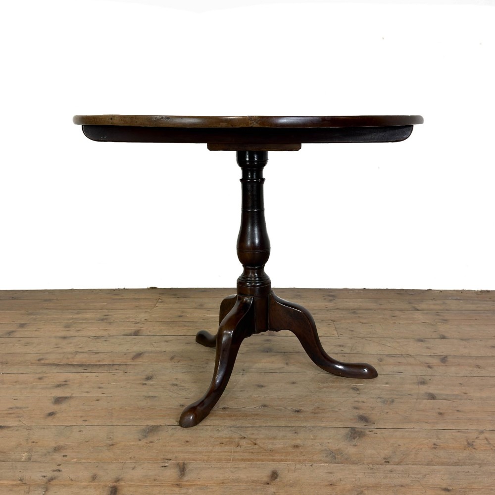 An antique George III mahogany tripod table featuring a circular tilt top shown in the upright position above a turned column and three down-swept legs. View VI
