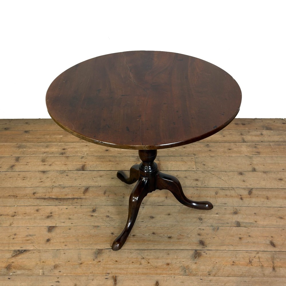 An antique George III mahogany tripod table featuring a circular tilt top shown in the upright position above a turned column and three down-swept legs. View VII