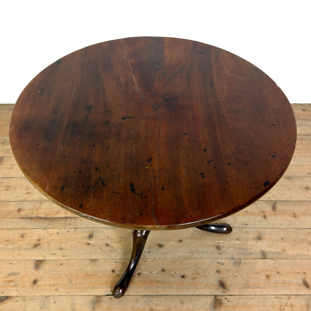 An antique George III mahogany tripod table featuring a circular tilt top shown in the upright position above a turned column and three down-swept legs. View VIII