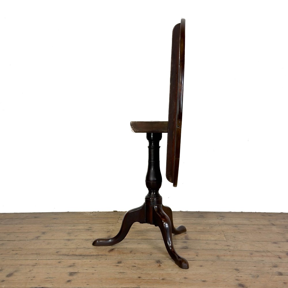 An antique George III mahogany tripod table featuring a circular tilt top shown in the upright position above a turned column and three down-swept legs. View XI