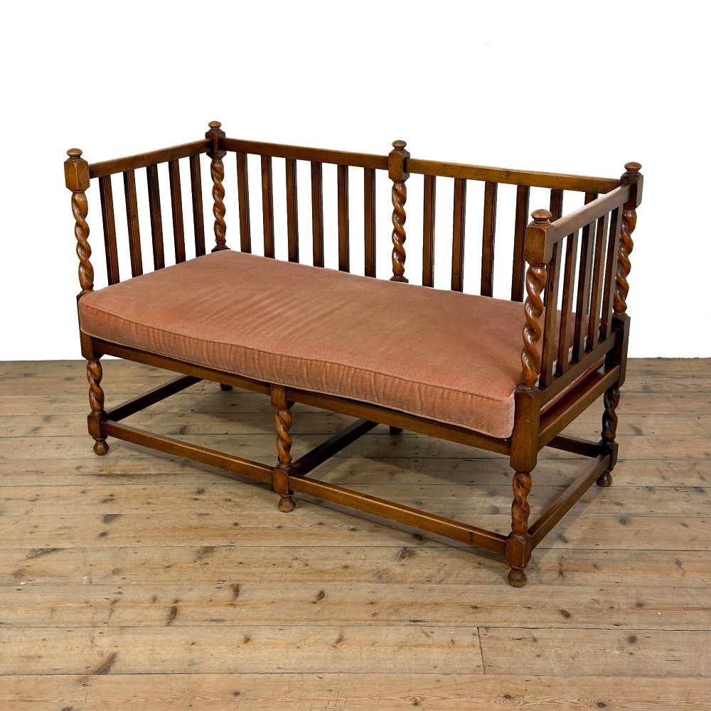 An Arts and Crafts style oak hall bench featuring barley twist legs and side posts, a vertical slat backrest, and a terracotta-coloured cushion. View III