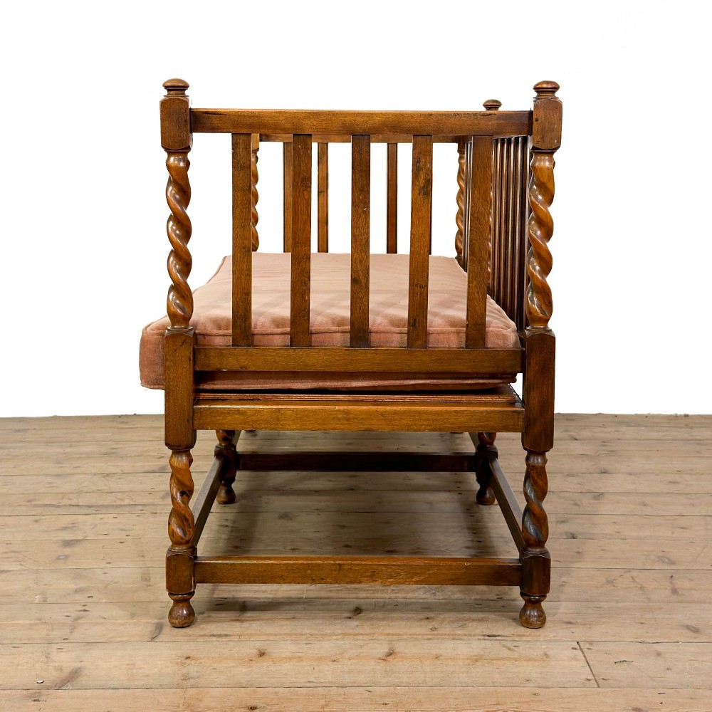 An Arts and Crafts style oak hall bench featuring barley twist legs and side posts, a vertical slat backrest, and a terracotta-coloured cushion. View IV