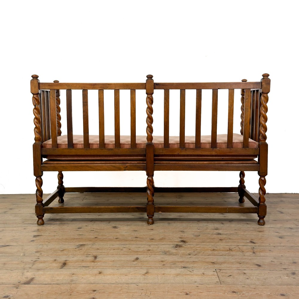 An Arts and Crafts style oak hall bench featuring barley twist legs and side posts, a vertical slat backrest, and a terracotta-coloured cushion. View V