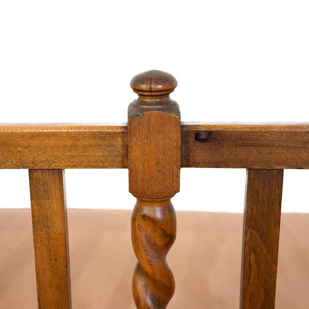 An Arts and Crafts style oak hall bench featuring barley twist legs and side posts, a vertical slat backrest, and a terracotta-coloured cushion. View VI