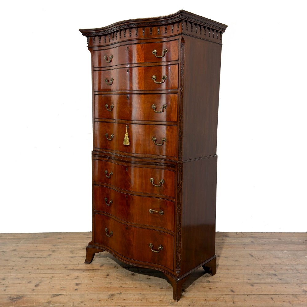 A tall mahogany serpentine chest on chest featuring two stacked sections of graduating drawers with brass handles and carved cornice detail. View II