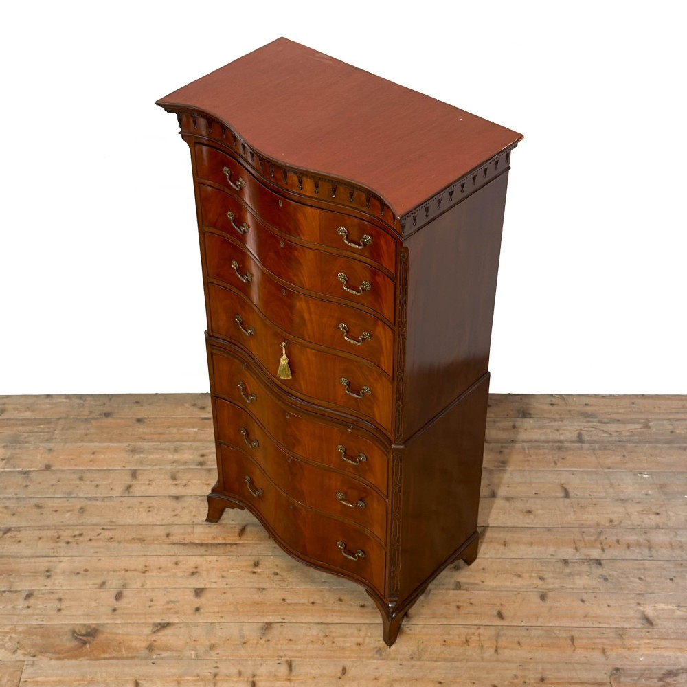 A tall mahogany serpentine chest on chest featuring two stacked sections of graduating drawers with brass handles and carved cornice detail. View III
