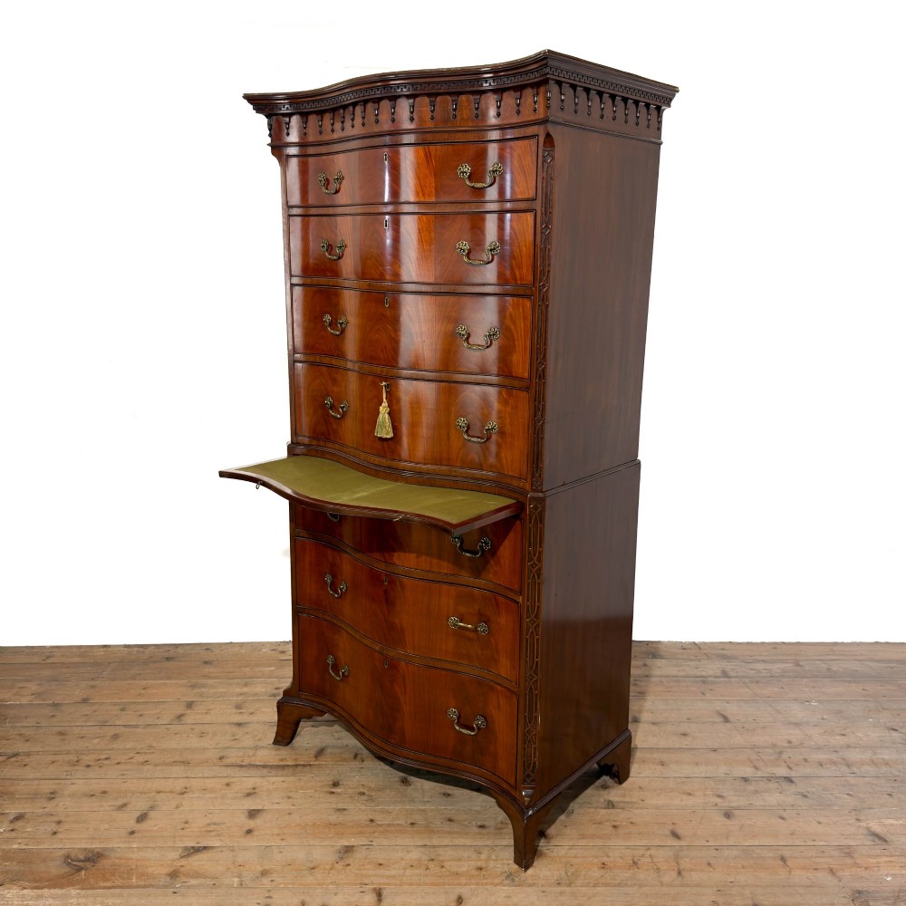 A tall mahogany serpentine chest on chest featuring two stacked sections of graduating drawers with brass handles and carved cornice detail. View V
