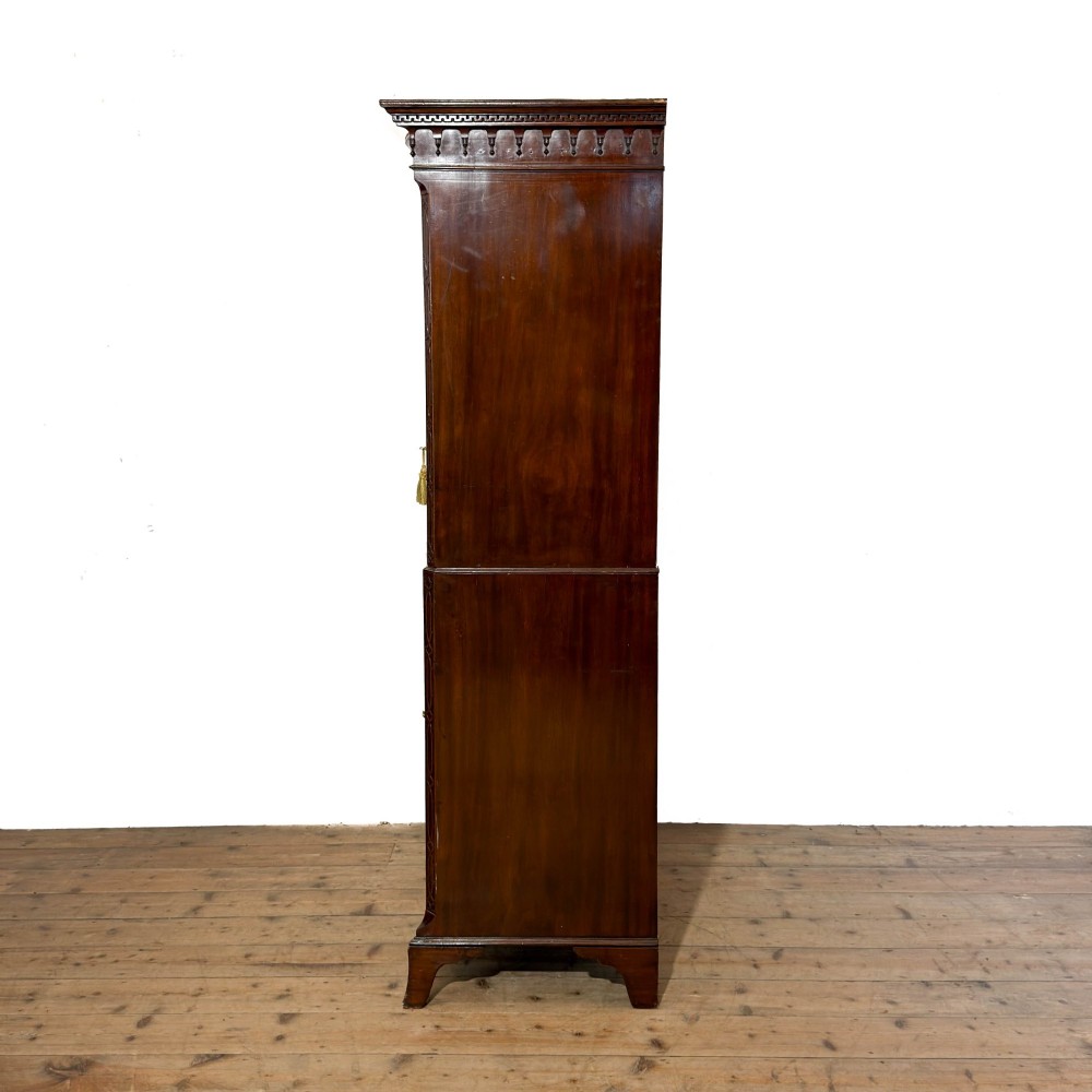 A tall mahogany serpentine chest on chest featuring two stacked sections of graduating drawers with brass handles and carved cornice detail. View VII