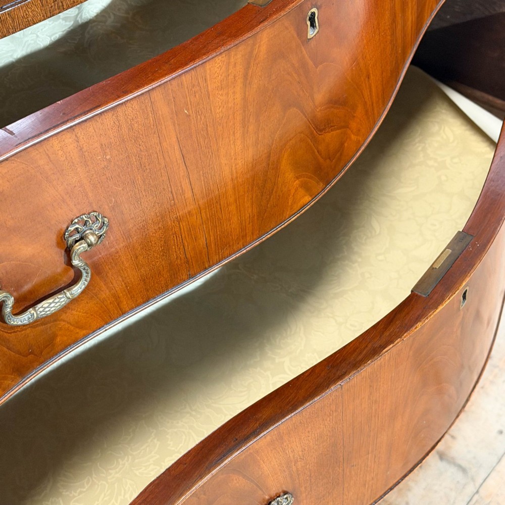 A tall mahogany serpentine chest on chest featuring two stacked sections of graduating drawers with brass handles and carved cornice detail. View VIII