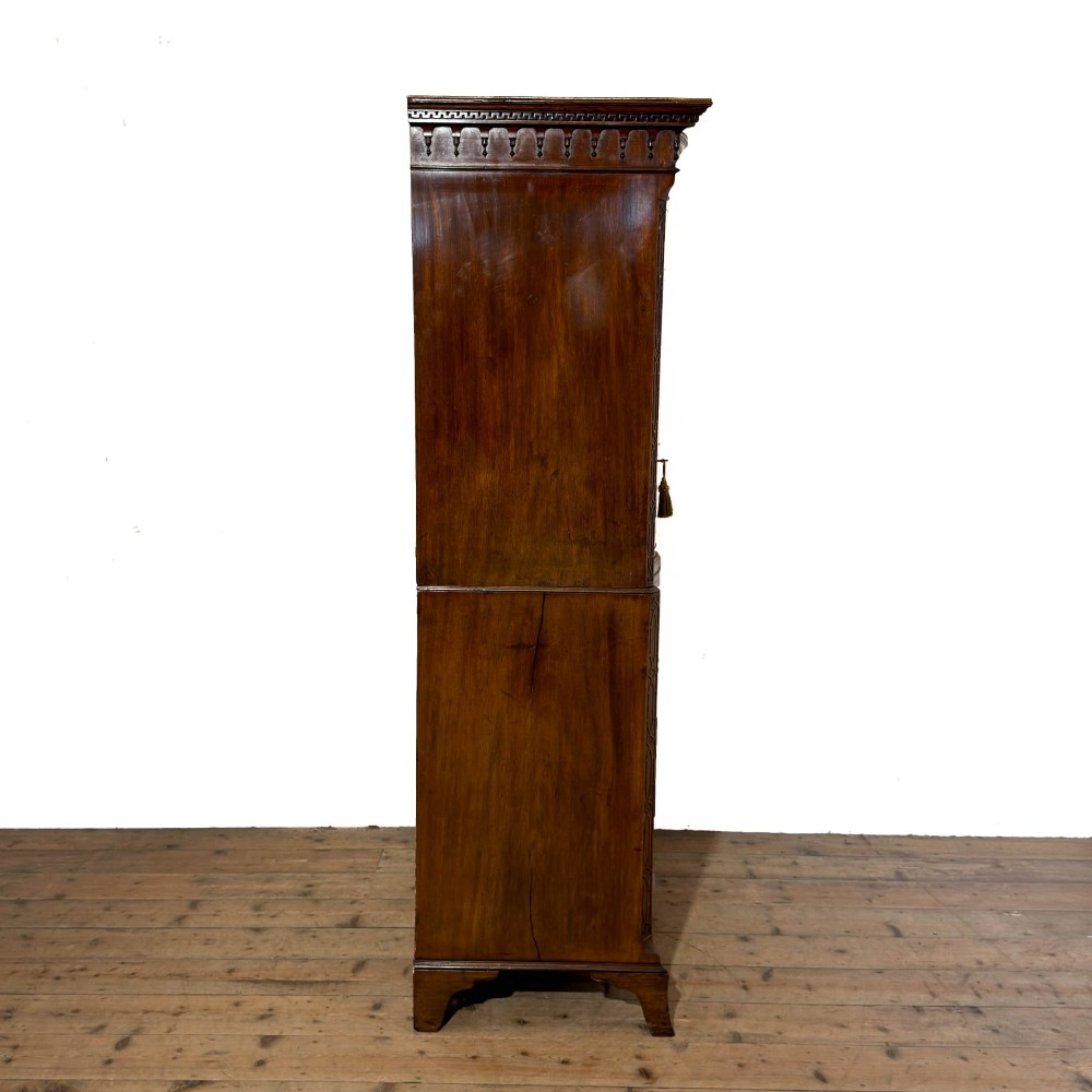A tall mahogany serpentine chest on chest featuring two stacked sections of graduating drawers with brass handles and carved cornice detail. View XI