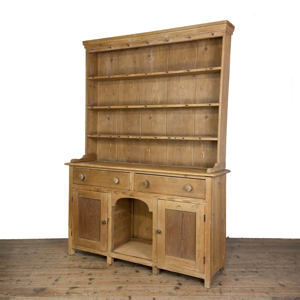 A tall Victorian pine kitchen dresser with open plate shelving, cup hooks, two drawers, panelled doors, and a central open alcove. View IV