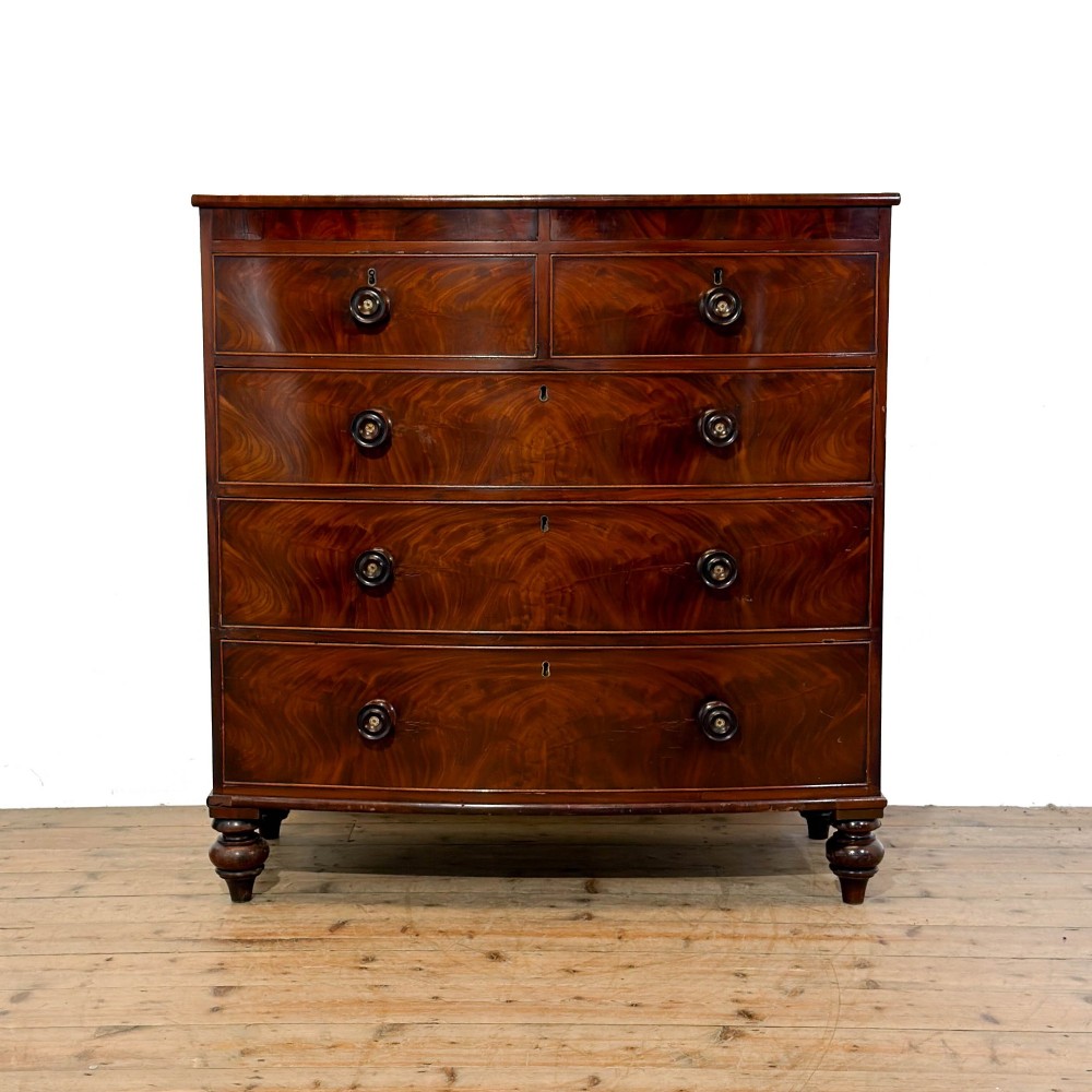 A Victorian mahogany bow front chest of drawers with two short over three long drawers, turned wooden knobs, and turned feet.