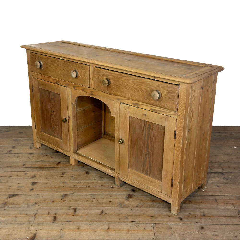 A Victorian pine dresser base featuring two top drawers with turned wooden knobs above two panelled cupboard doors and a central open arched niche. View IV