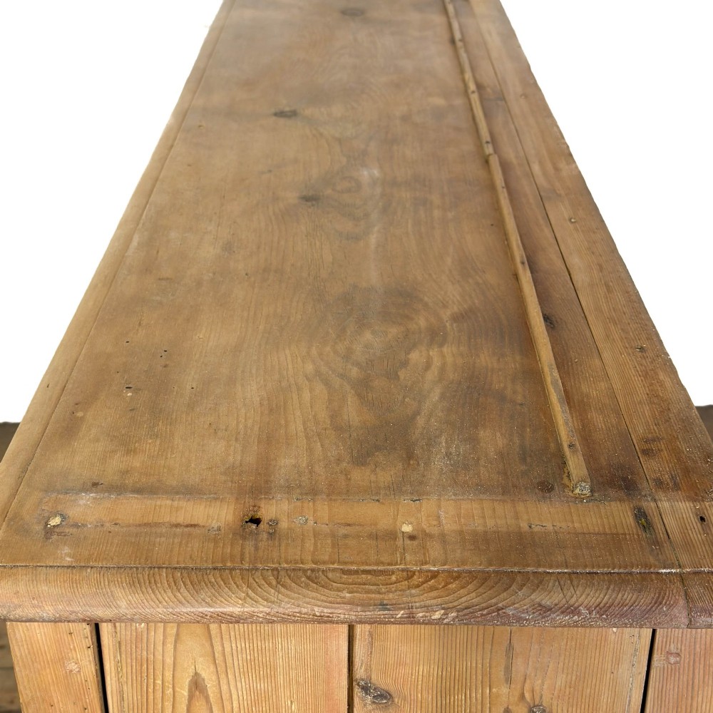 A Victorian pine dresser base featuring two top drawers with turned wooden knobs above two panelled cupboard doors and a central open arched niche. View VII