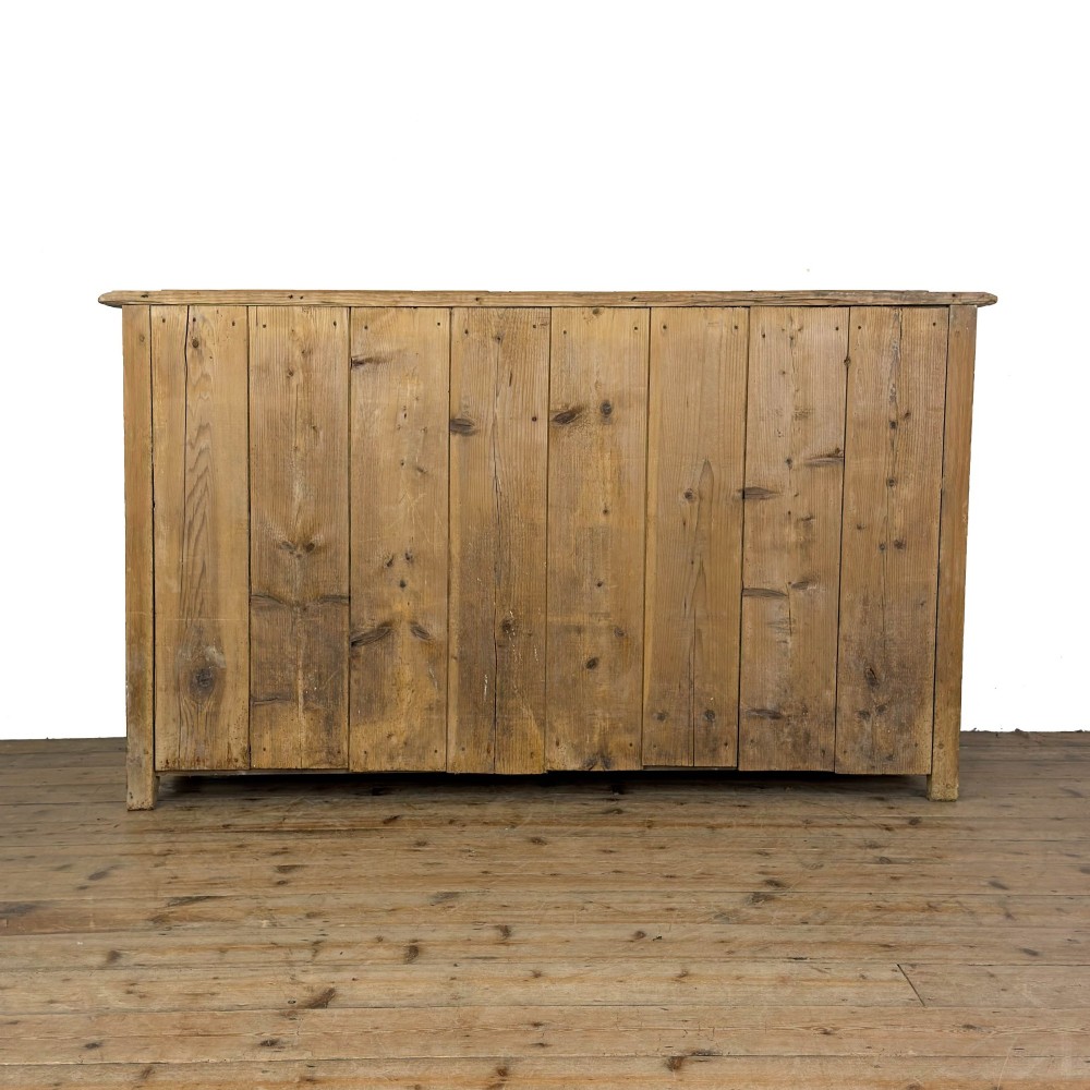 A Victorian pine dresser base featuring two top drawers with turned wooden knobs above two panelled cupboard doors and a central open arched niche. View VIII