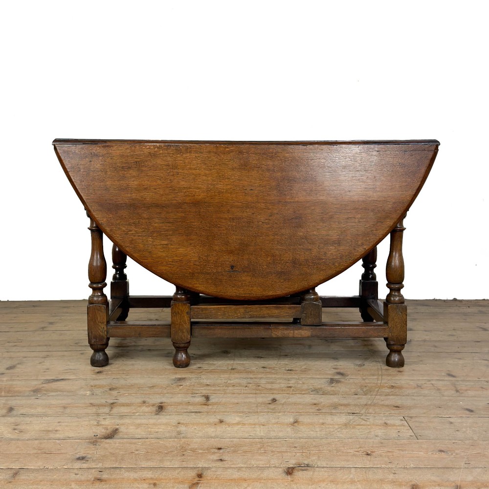 An 18th-century dark oak gateleg table featuring two hinged drop leaves, turned legs, and lower stretchers. View II