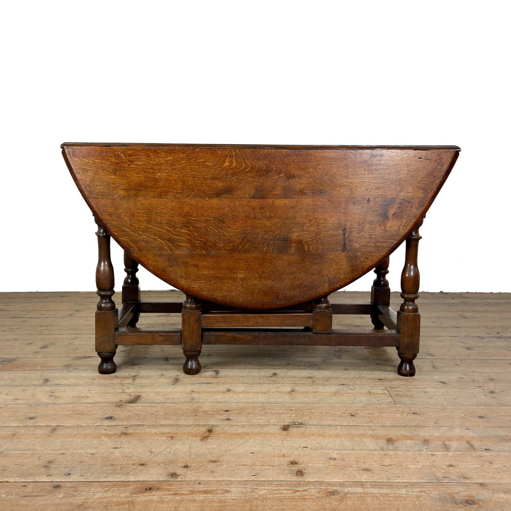 An 18th-century dark oak gateleg table featuring two hinged drop leaves, turned legs, and lower stretchers. View IV