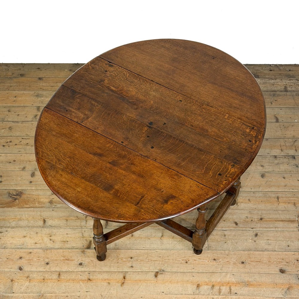 An 18th-century dark oak gateleg table featuring two hinged drop leaves, turned legs, and lower stretchers. View VI