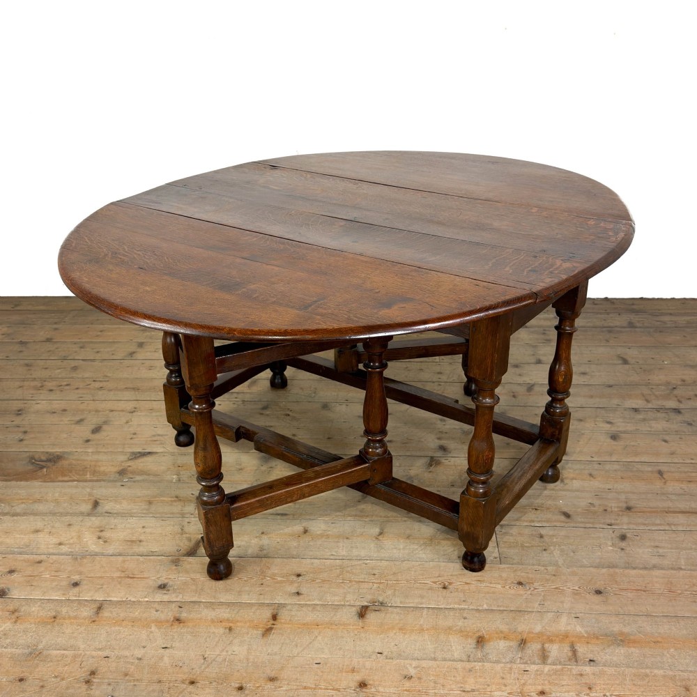 An 18th-century dark oak gateleg table featuring two hinged drop leaves, turned legs, and lower stretchers. View VII