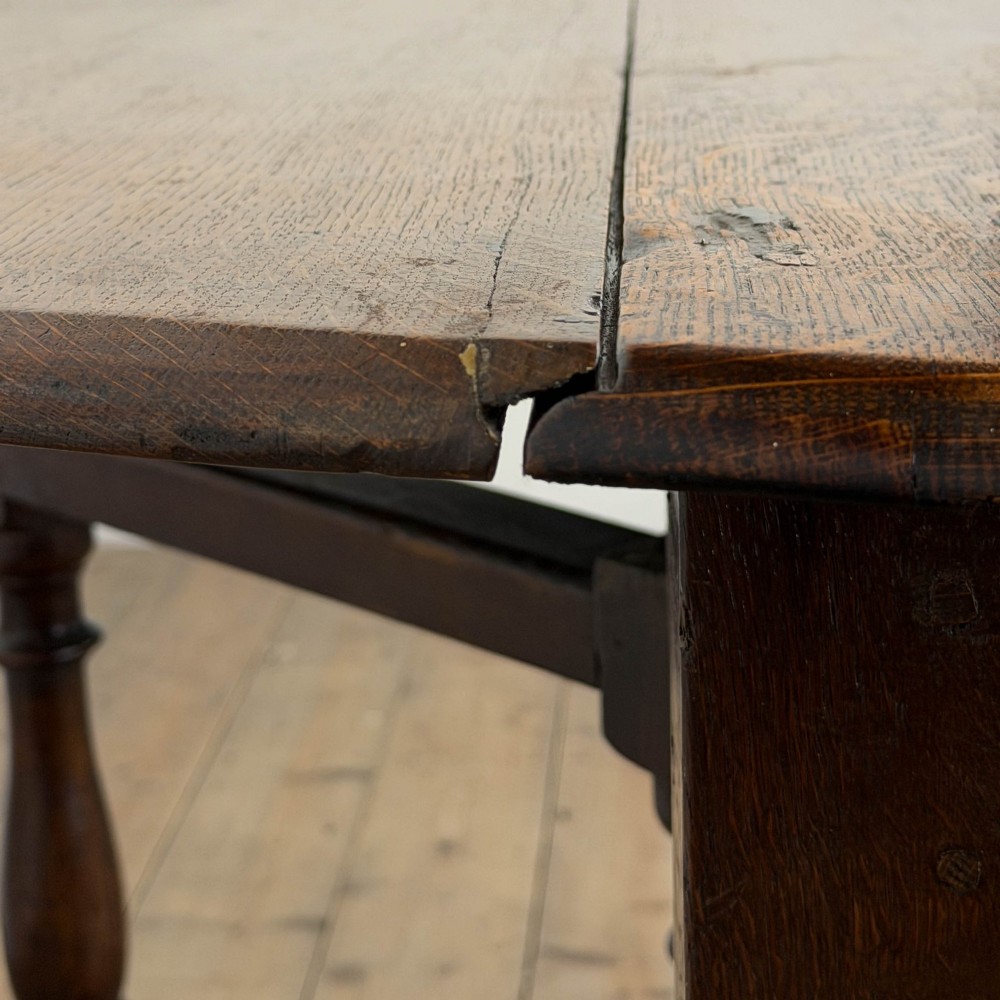 An 18th-century dark oak gateleg table featuring two hinged drop leaves, turned legs, and lower stretchers. View X