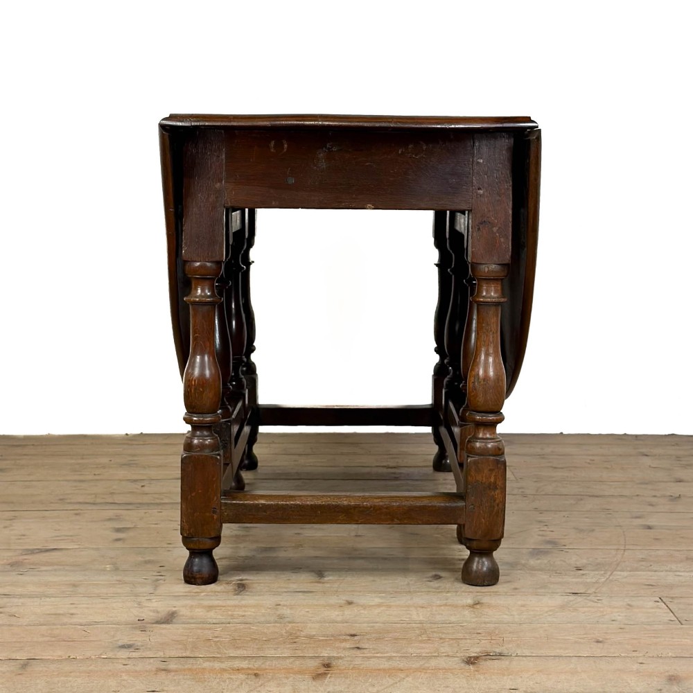 An 18th-century dark oak gateleg table featuring two hinged drop leaves, turned legs, and lower stretchers. View XI