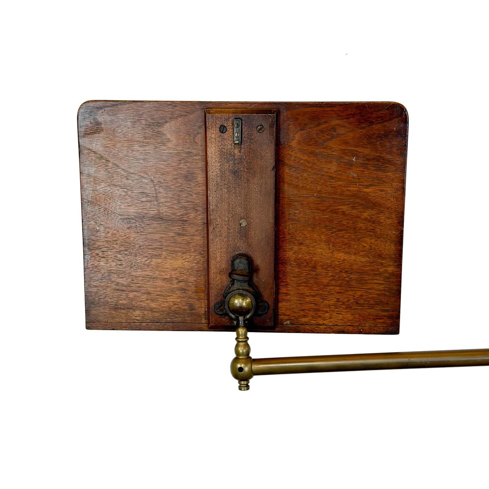 A Victorian adjustable reading stand featuring a cast iron decorative base, a brass column with an articulated swing arm, and a rectangular mahogany book rest. View VI