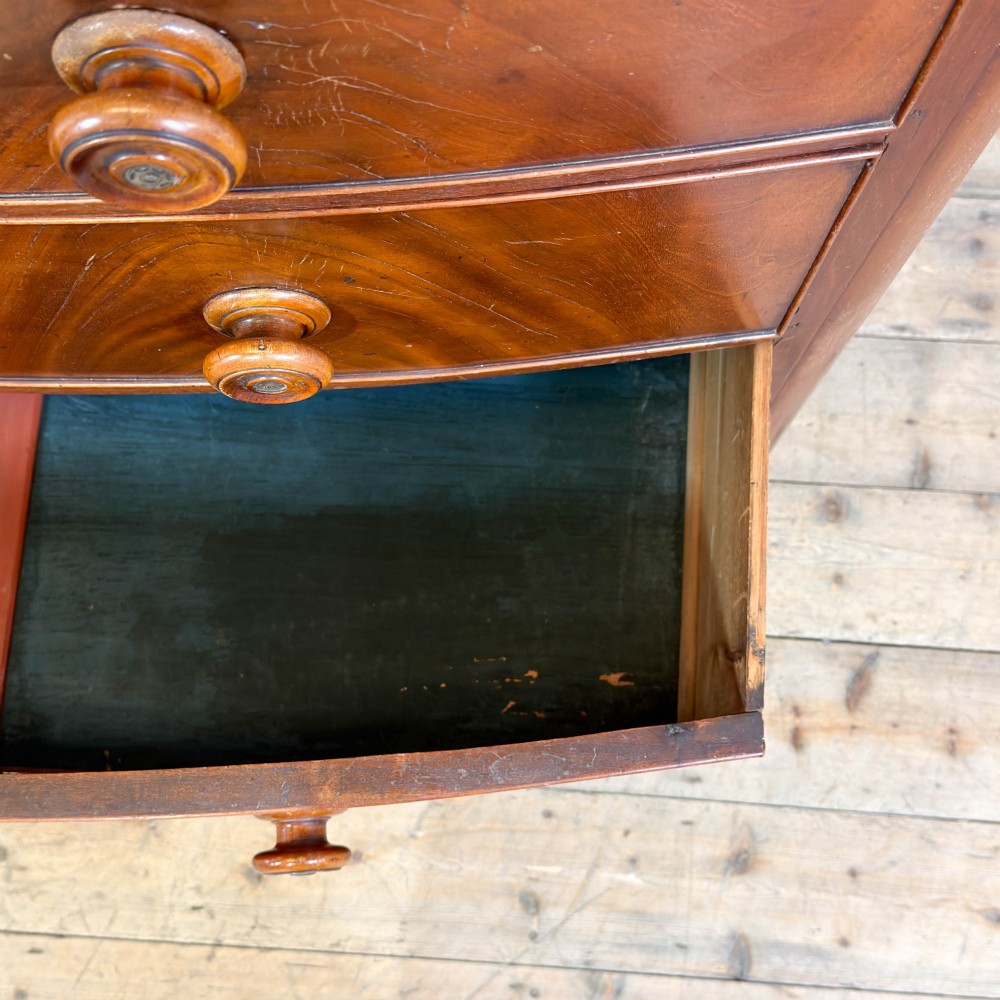 A Victorian mahogany chest of drawers featuring two short drawers over three long drawers with turned wooden knobs and a scalloped lower apron. View III