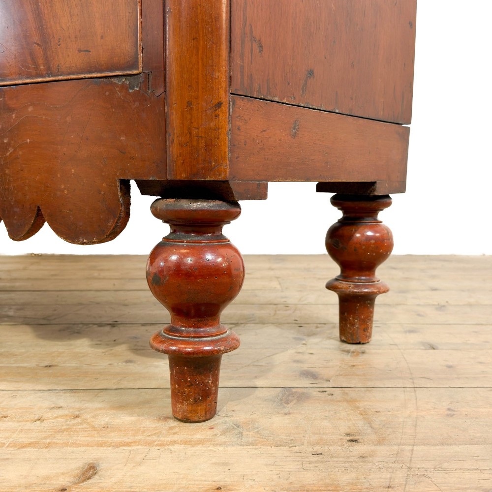 A Victorian mahogany chest of drawers featuring two short drawers over three long drawers with turned wooden knobs and a scalloped lower apron. View VIII