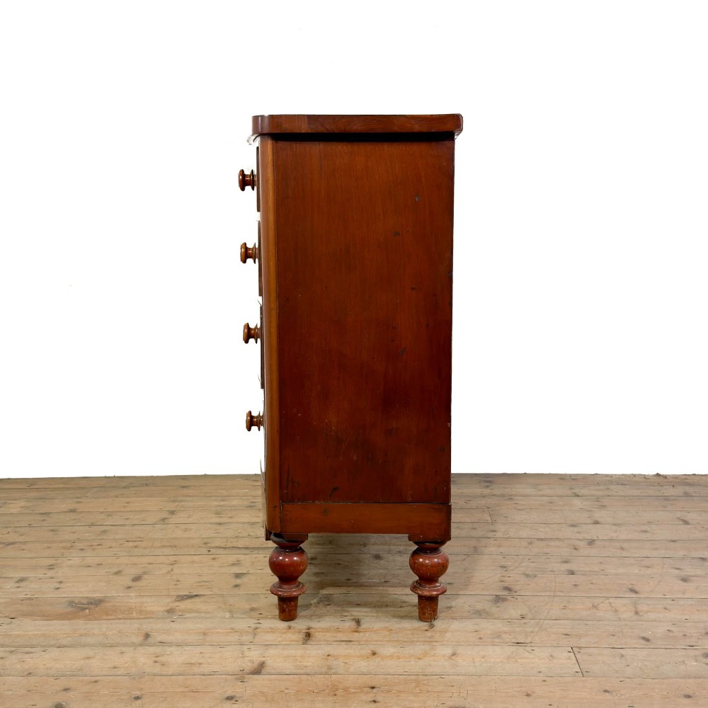 A Victorian mahogany chest of drawers featuring two short drawers over three long drawers with turned wooden knobs and a scalloped lower apron. View IX