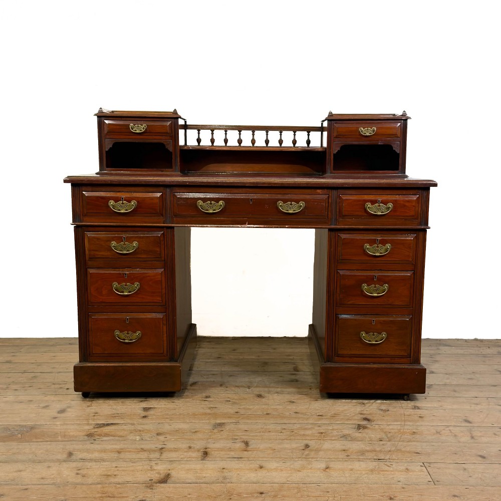 An antique Victorian mahogany pedestal desk featuring a raised gallery superstructure, multiple drawers, and brass handles.