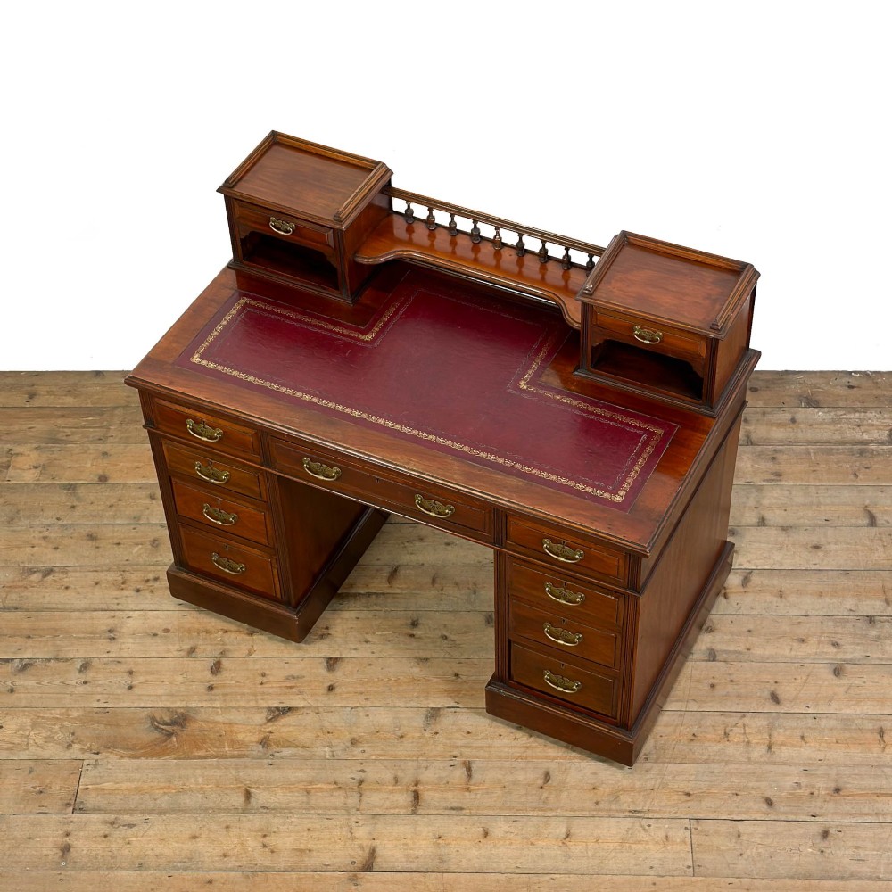 An antique Victorian mahogany pedestal desk featuring a raised gallery superstructure, multiple drawers, and brass handles. View III