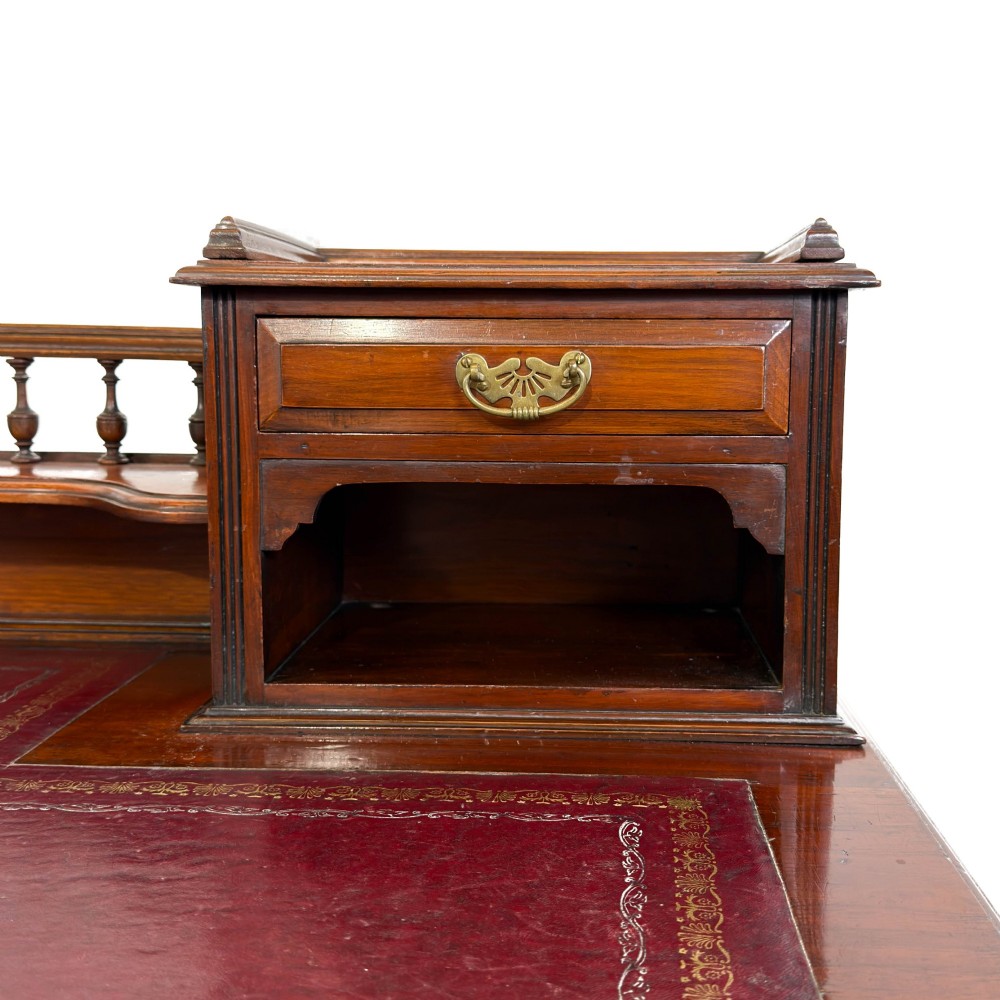 An antique Victorian mahogany pedestal desk featuring a raised gallery superstructure, multiple drawers, and brass handles. View VII
