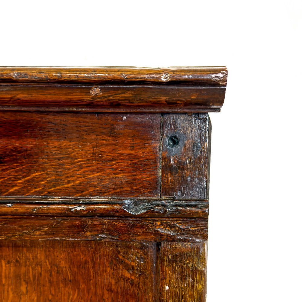 A seventeenth-century style carved oak coffer featuring geometric panelling, split baluster turnings, and dark square inlay details on a plinth base. View IV