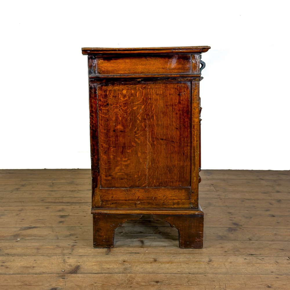 A seventeenth-century style carved oak coffer featuring geometric panelling, split baluster turnings, and dark square inlay details on a plinth base. View VIII