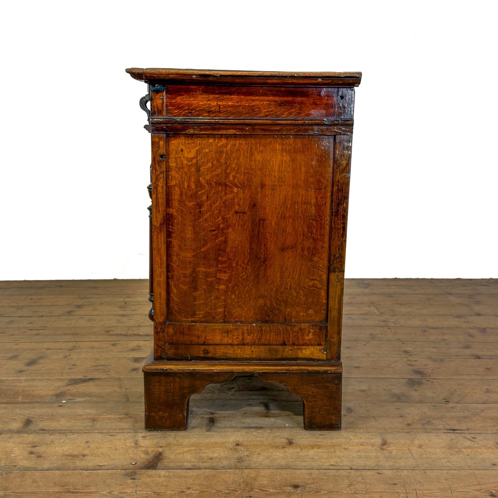 A seventeenth-century style carved oak coffer featuring geometric panelling, split baluster turnings, and dark square inlay details on a plinth base. View X
