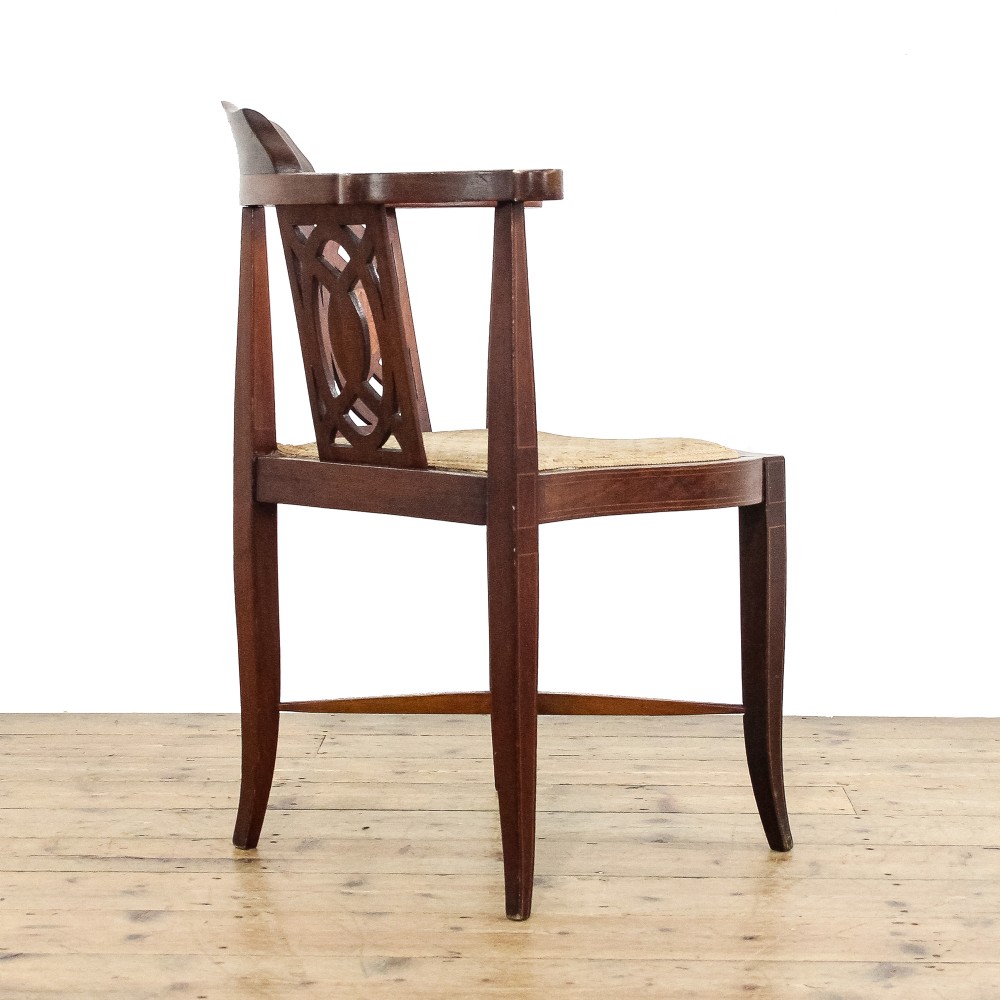 An antique Edwardian mahogany corner armchair featuring inlaid marquetry oval patera, two pierced back splats, tapered legs, and a patterned fabric seat. View II