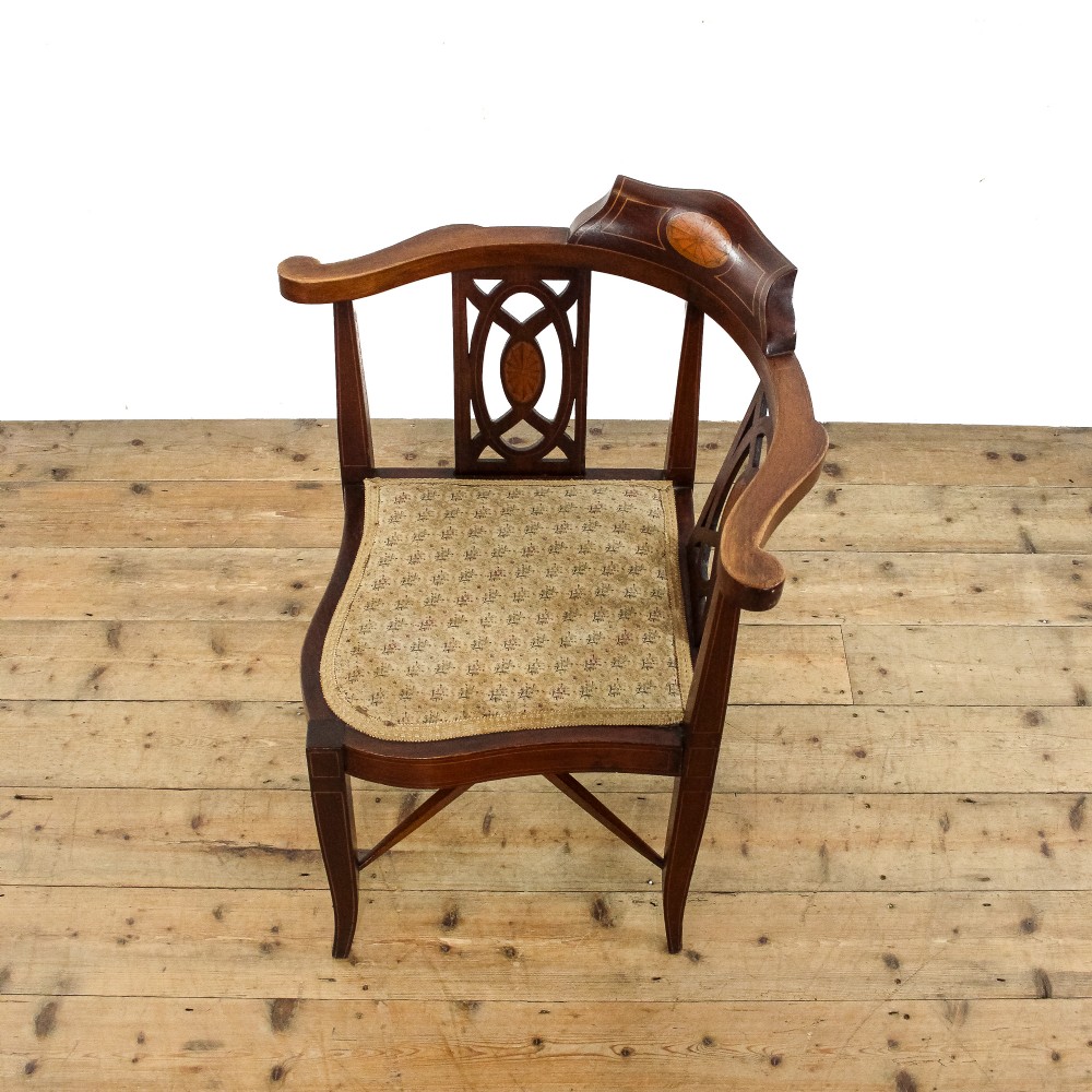 An antique Edwardian mahogany corner armchair featuring inlaid marquetry oval patera, two pierced back splats, tapered legs, and a patterned fabric seat. View V