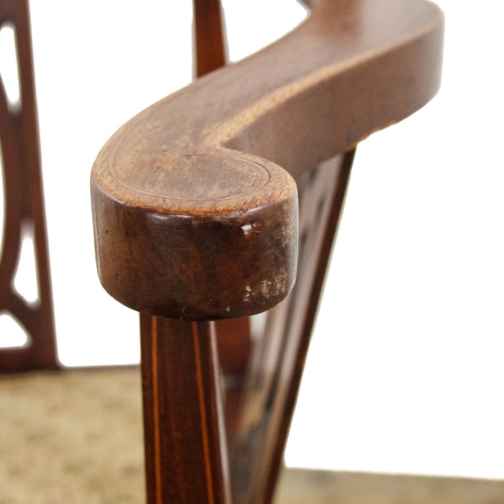An antique Edwardian mahogany corner armchair featuring inlaid marquetry oval patera, two pierced back splats, tapered legs, and a patterned fabric seat. View X