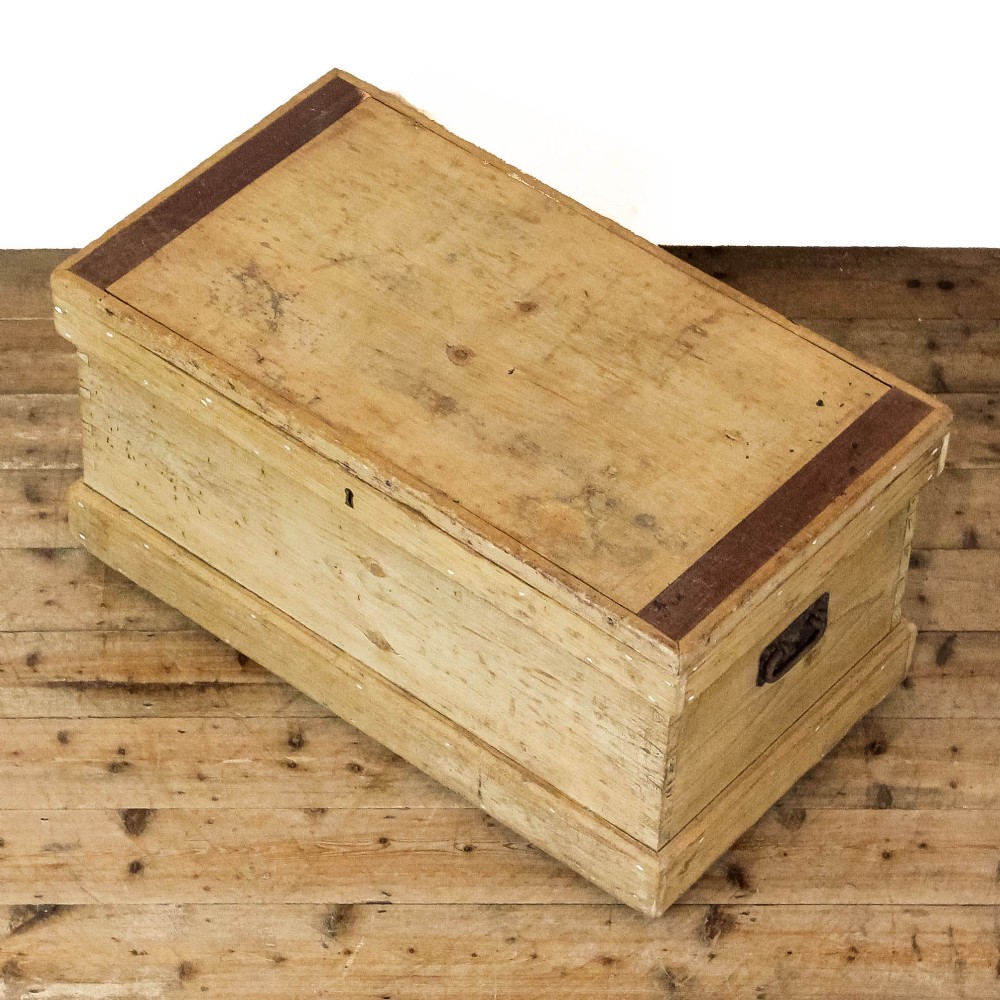 A rectangular natural pine storage chest featuring visible hand-cut dovetail joinery, a fitted flat lid, a central keyhole escutcheon, and a thick timber plinth base. View III
