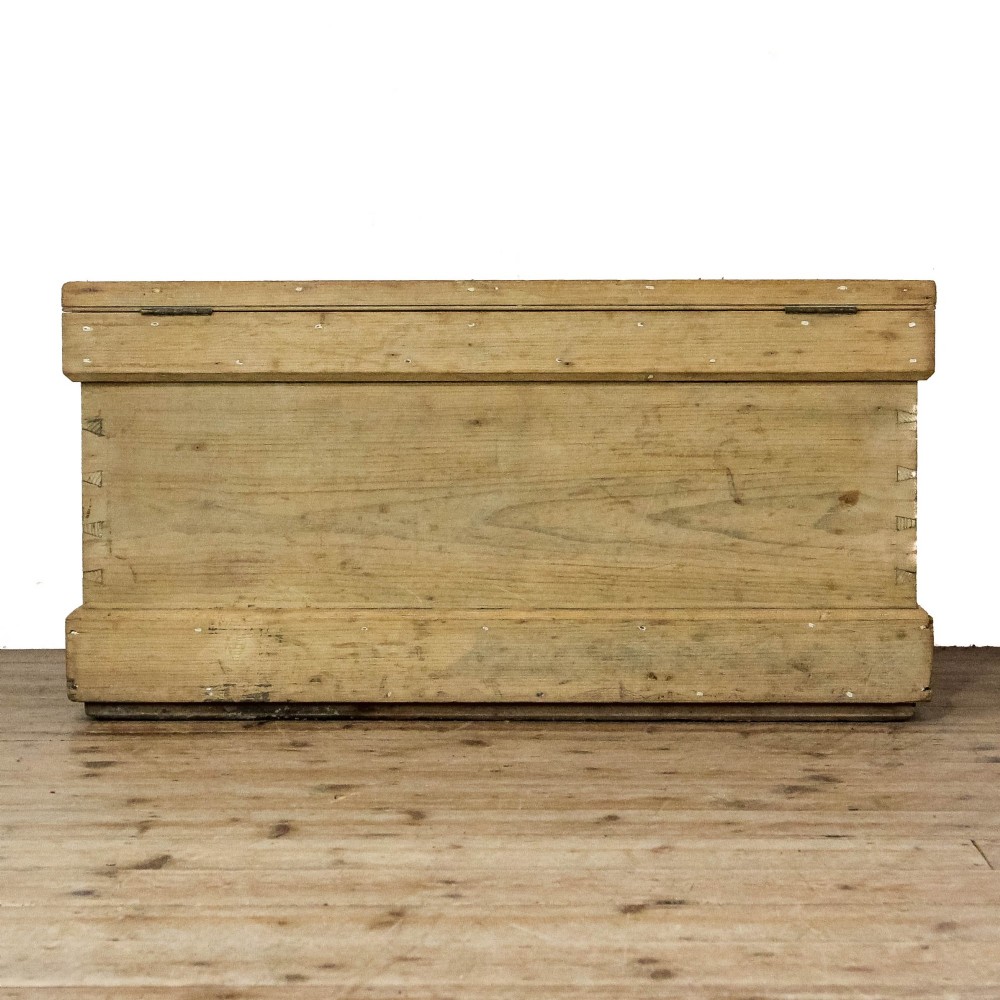 A rectangular natural pine storage chest featuring visible hand-cut dovetail joinery, a fitted flat lid, a central keyhole escutcheon, and a thick timber plinth base. View VII
