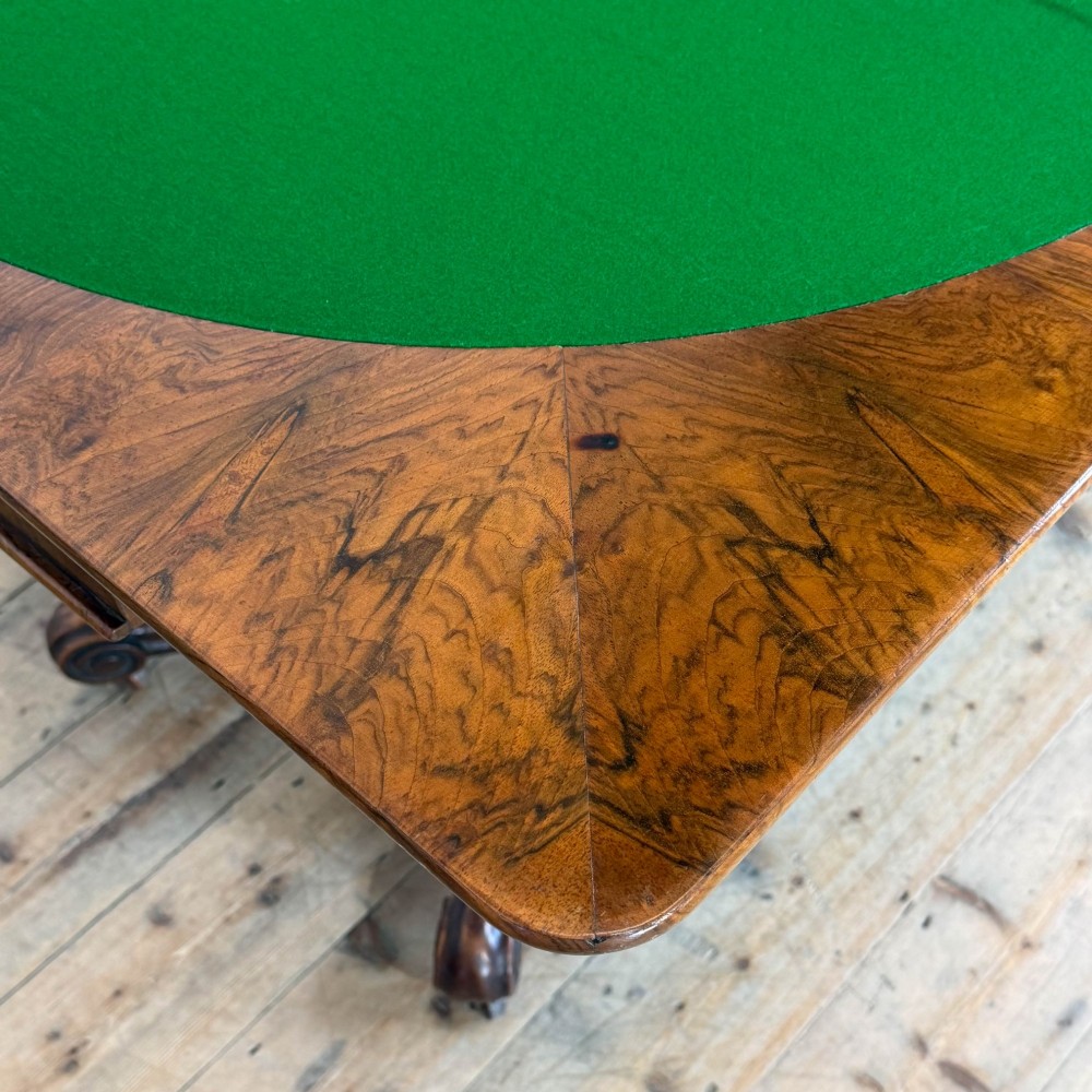 An antique Victorian walnut foldover card table featuring a rectangular swivel top, turned central column, and carved scroll feet. View IV