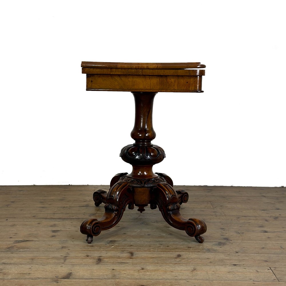 An antique Victorian walnut foldover card table featuring a rectangular swivel top, turned central column, and carved scroll feet. View VI