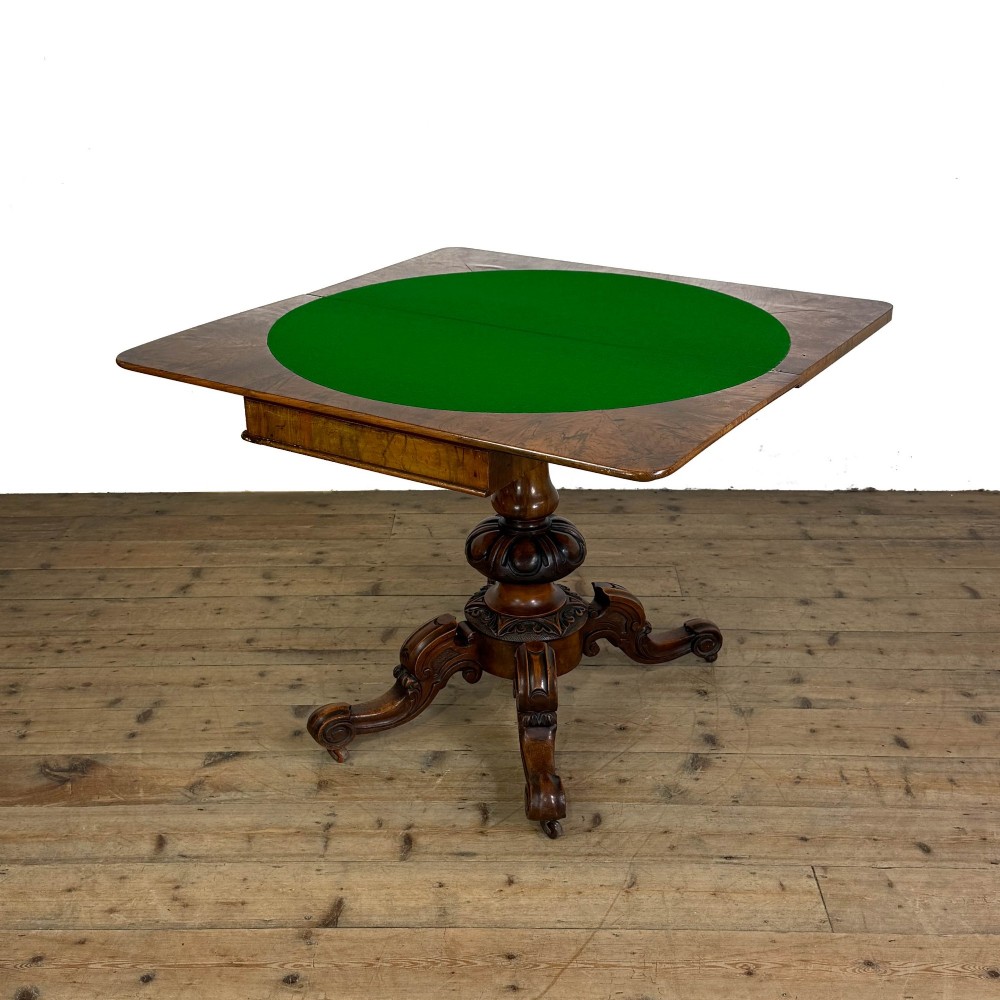 An antique Victorian walnut foldover card table featuring a rectangular swivel top, turned central column, and carved scroll feet. View IX