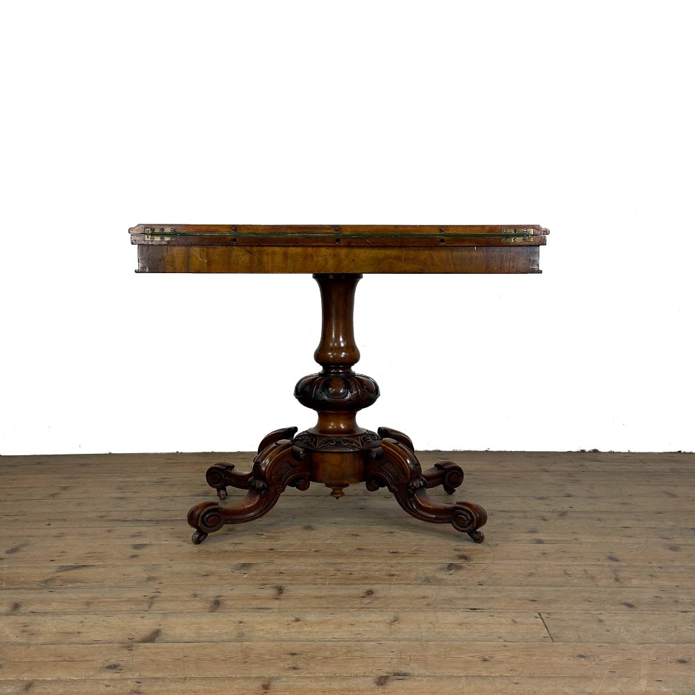 An antique Victorian walnut foldover card table featuring a rectangular swivel top, turned central column, and carved scroll feet. View X