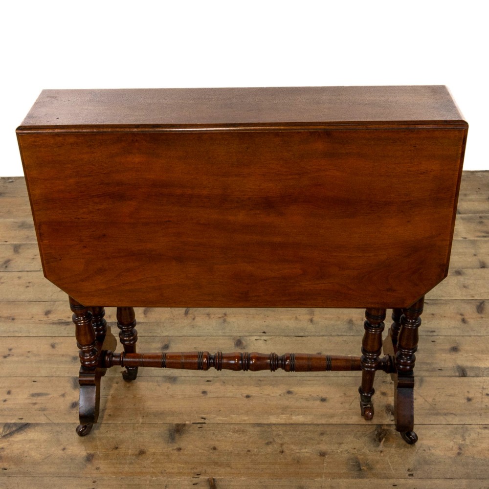An antique Victorian walnut Sutherland table featuring turned legs, a drop-leaf top, a cross stretcher, and small castors. View IX