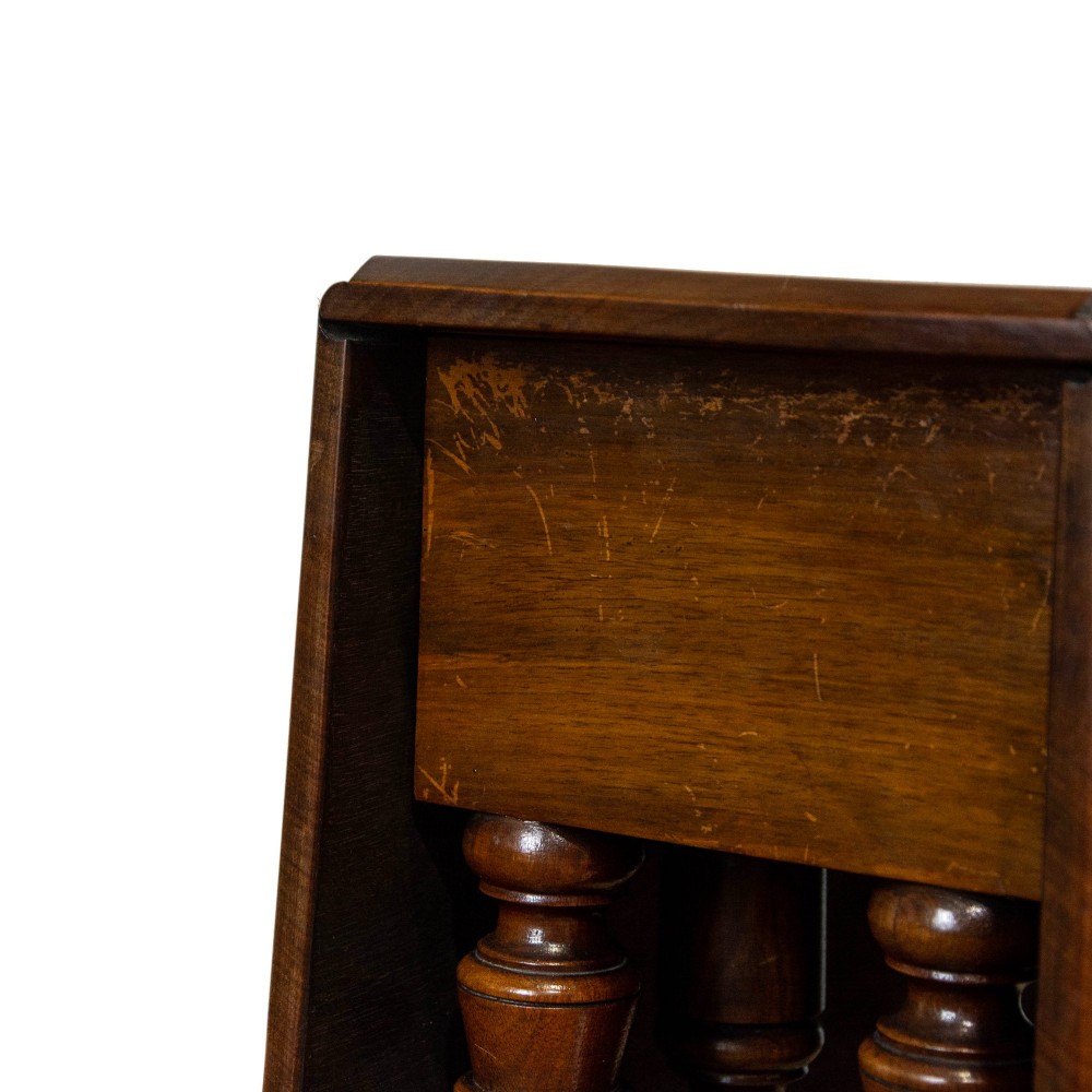 An antique Victorian walnut Sutherland table featuring turned legs, a drop-leaf top, a cross stretcher, and small castors. View X