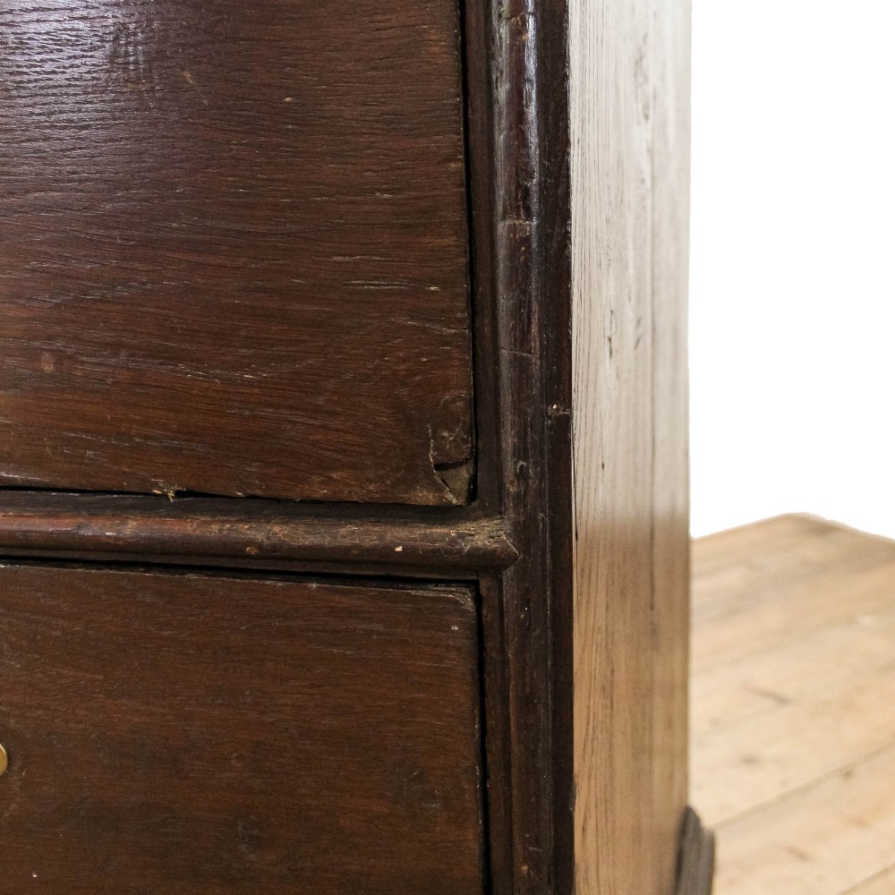 An eighteenth-century dark oak chest of drawers featuring a two-over-three drawer configuration, brass swan-neck handles, decorative keyhole escutcheons, and shaped bracket feet. View II