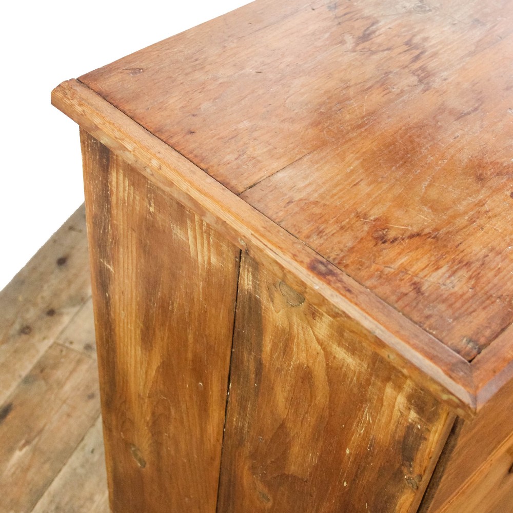 An antique pine chest of drawers featuring three wide drawers with turned wooden knob handles and a low plinth base. View II