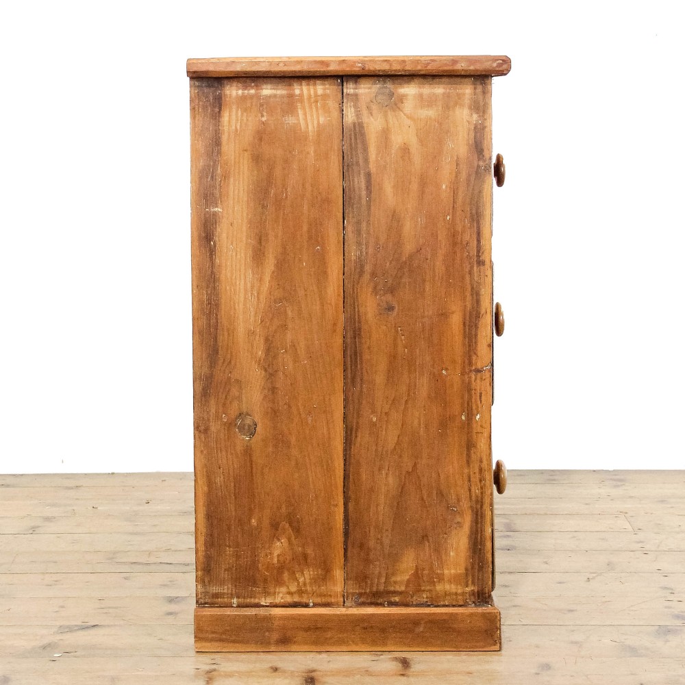 An antique pine chest of drawers featuring three wide drawers with turned wooden knob handles and a low plinth base. View III