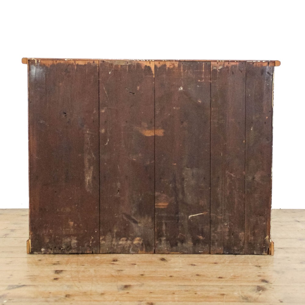 An antique pine chest of drawers featuring three wide drawers with turned wooden knob handles and a low plinth base. View IV
